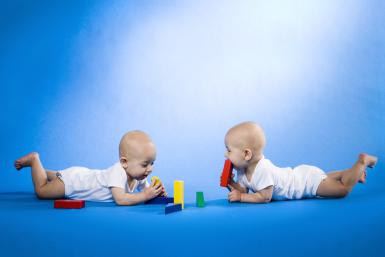 Twin babies on bellies with blocks